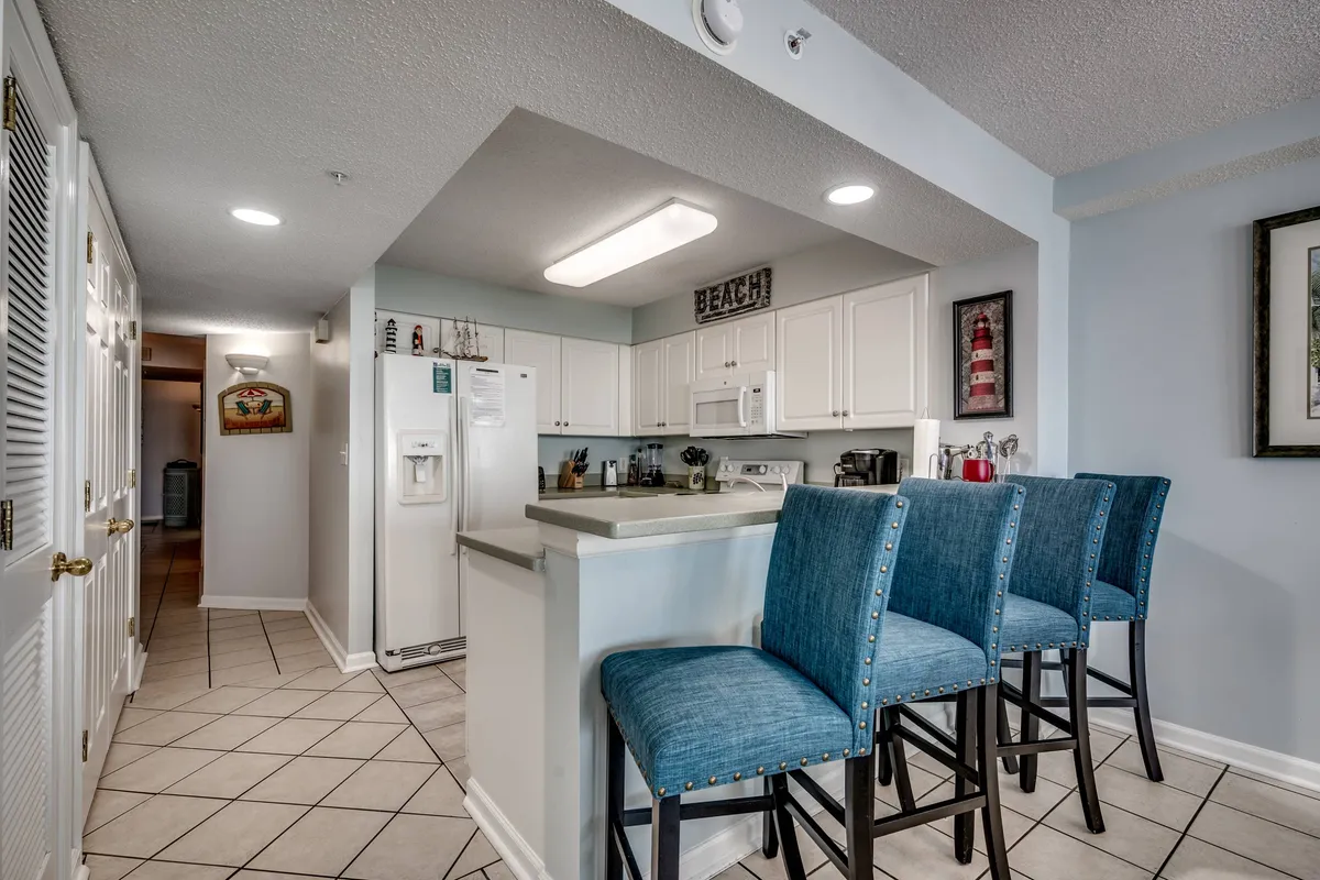 A relaxed, welcoming kitchen scene featuring a kitchen island with bar stools, modern appliances, and decorative wall art. The open layout encourages both cooking and casual dining or entertaining, making it perfect for group experiences.