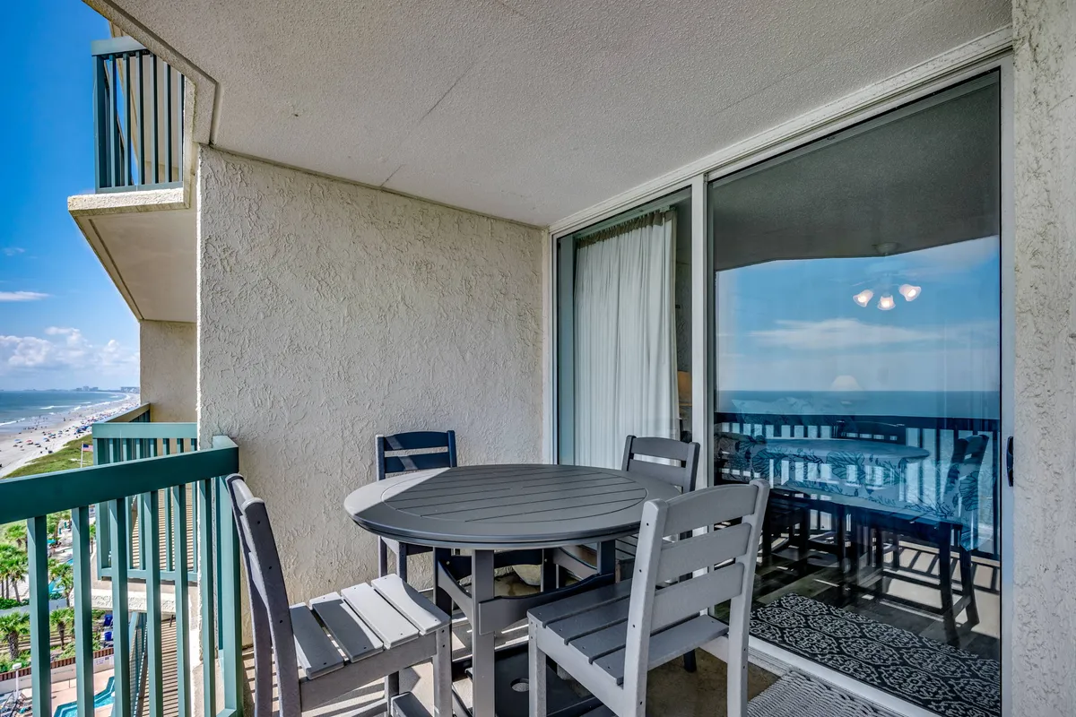 A tranquil balcony scene featuring an outdoor dining table set against a backdrop of the sea. The space is ideal for relaxing meals or post-round gatherings, highlighting opportunities for relaxation and socializing after a day of golf.