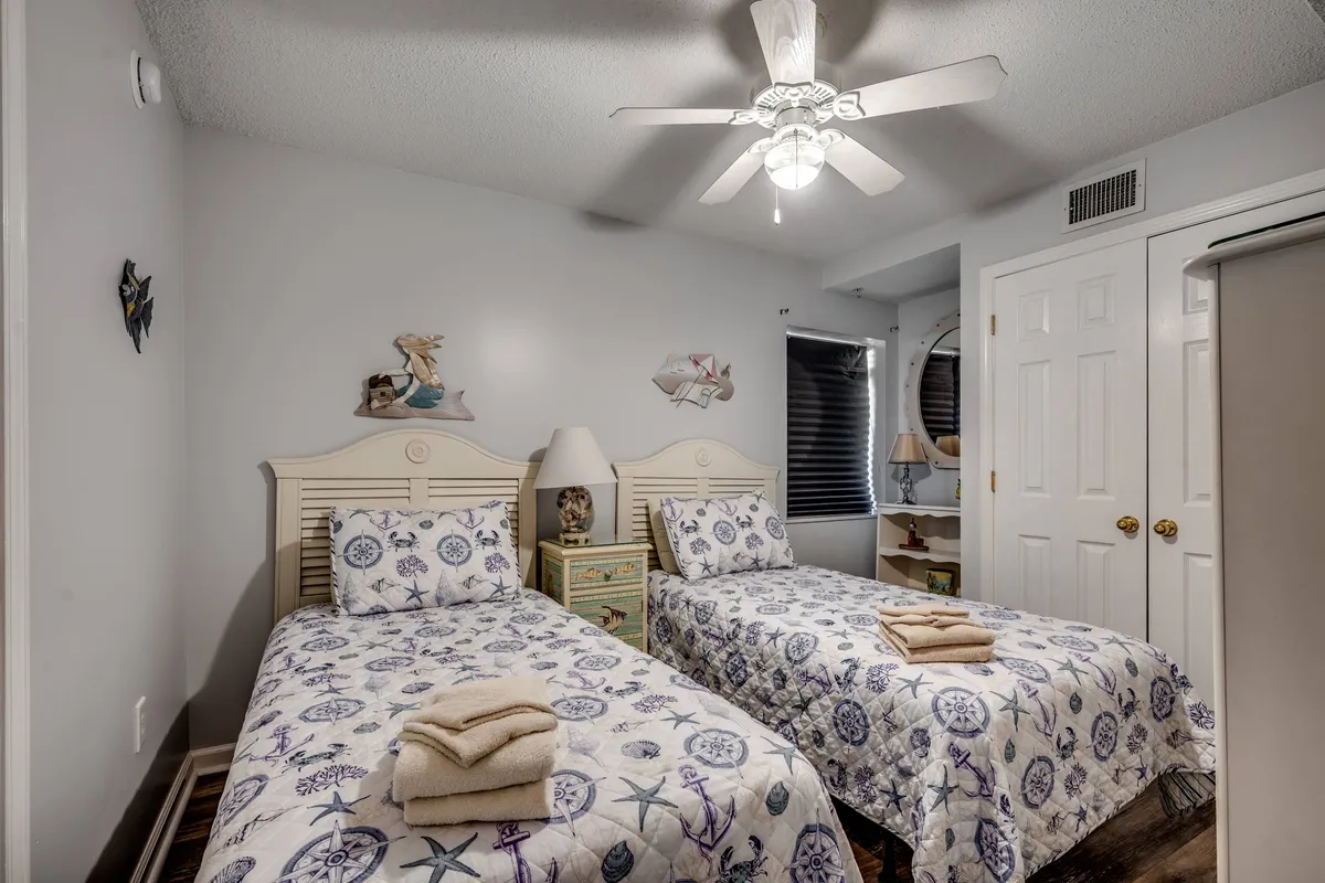 A cheerful twin bedroom decorated with nautical-themed bedding, bedside lamps, light wood furniture, and playful wall art. The space feels bright and inviting—ideal for children or solo guests seeking their own retreat.